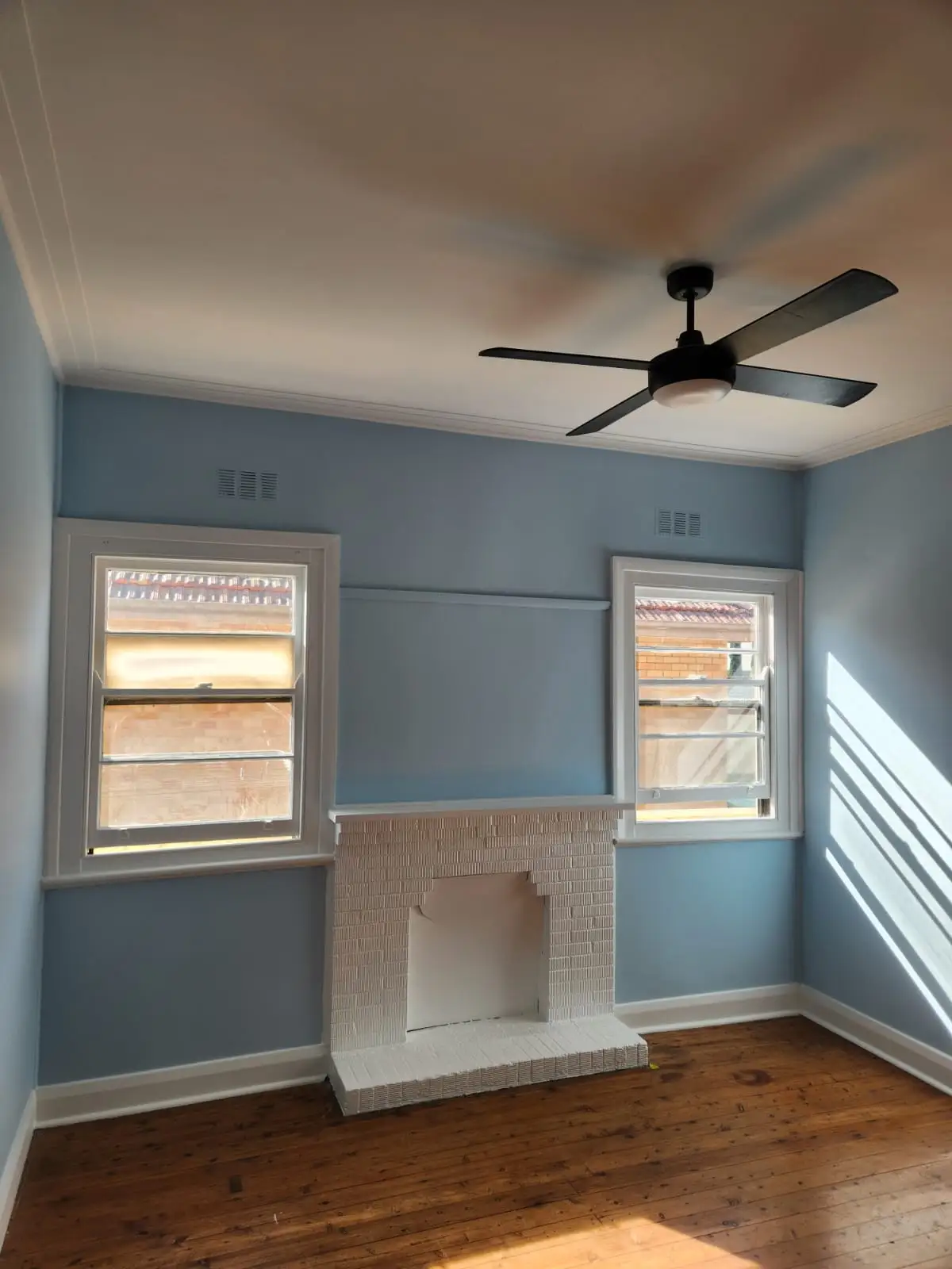 Bedroom painted in soft blue with white trim and a white fireplace