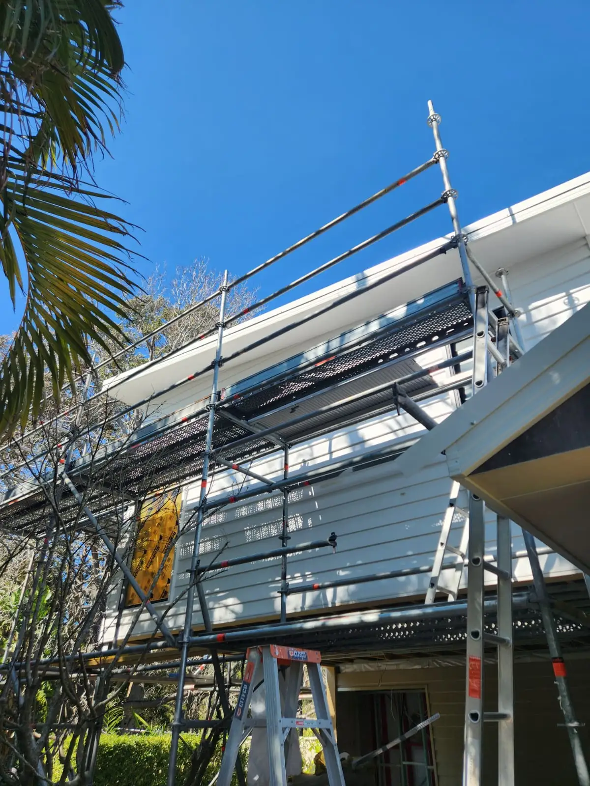 A Newcastle house under scaffolding for an exterior repaint on a clear day