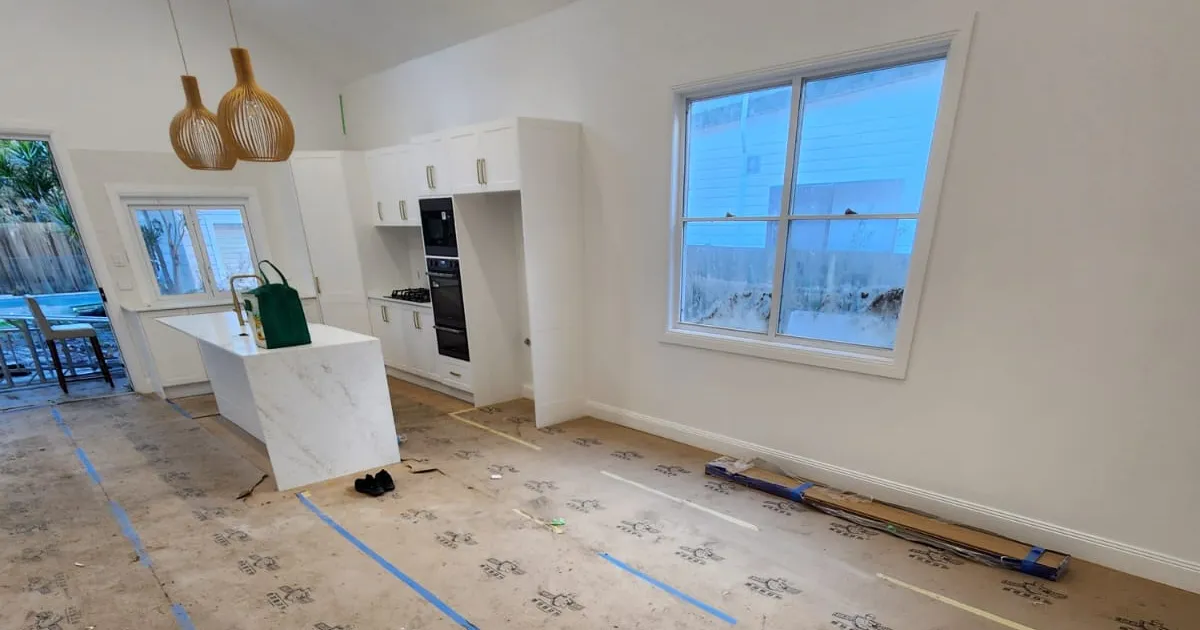 Open-plan kitchen with the floor covered and taped before painting starts