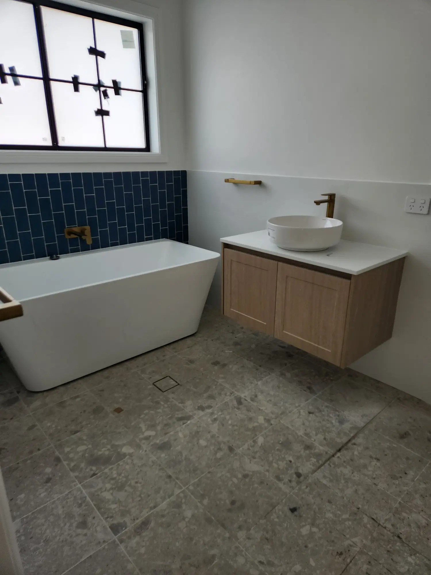 Bathroom with navy tiled wall, freestanding bath and timber vanity