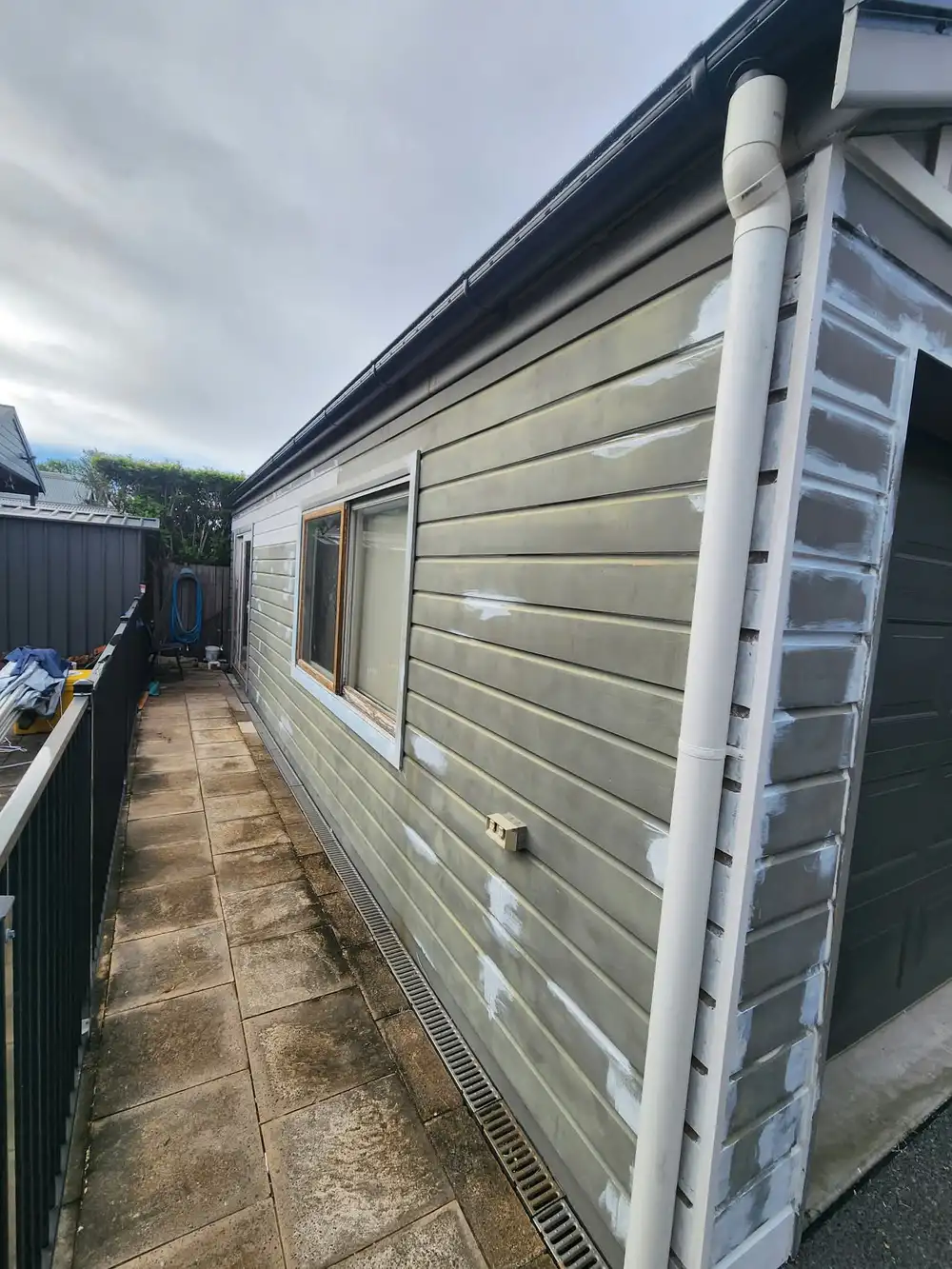 The same garage wall during prep, with white patches along the weatherboards