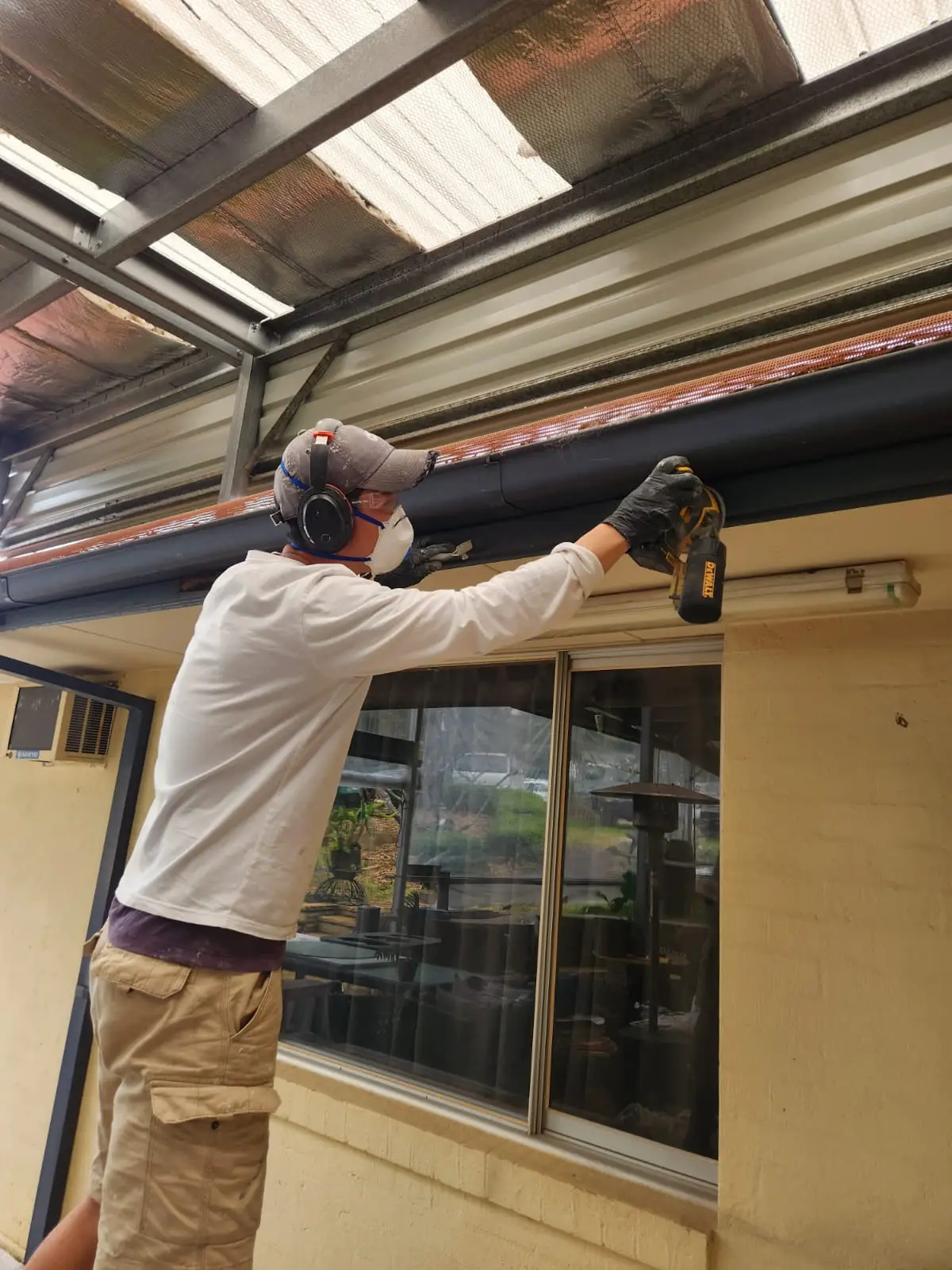 Painter in a respirator coating guttering above a shopfront